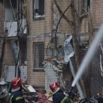 two firemen are spraying water on a building