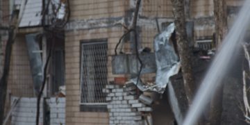 two firemen are spraying water on a building