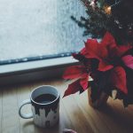 mug of coffee beside christmass tree by the window