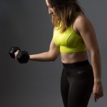 woman wearing pink sports bra holding dumbbells