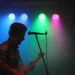 man playing guitar with stage lights