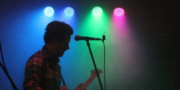 man playing guitar with stage lights