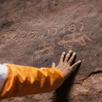 a person with their hand on a rock