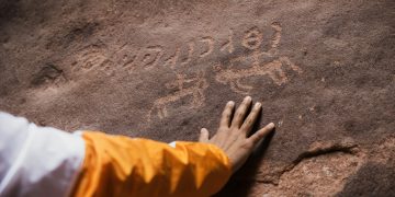 a person with their hand on a rock