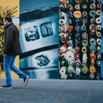 man walking near multicolored painted wall