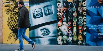 man walking near multicolored painted wall