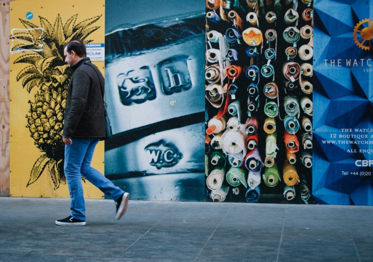 man walking near multicolored painted wall