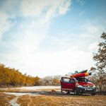 red vehicle on dirt road near trees at daytime