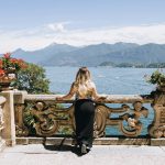 A woman is sitting on a balcony overlooking the water