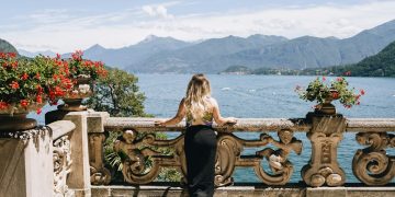 A woman is sitting on a balcony overlooking the water